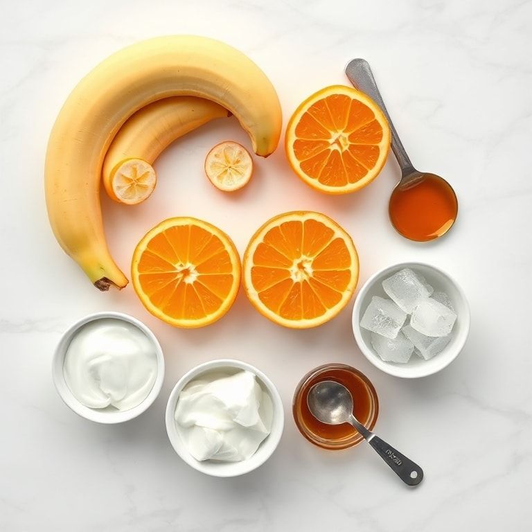 Raw ingredients for orange banana smoothie including bananas, oranges, yogurt, honey, and ice cubes arranged on white marble surface