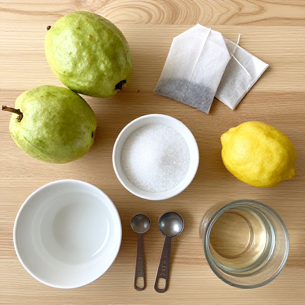 Guava, white tea bags, lemon, sugar, and water arranged on a wooden surface