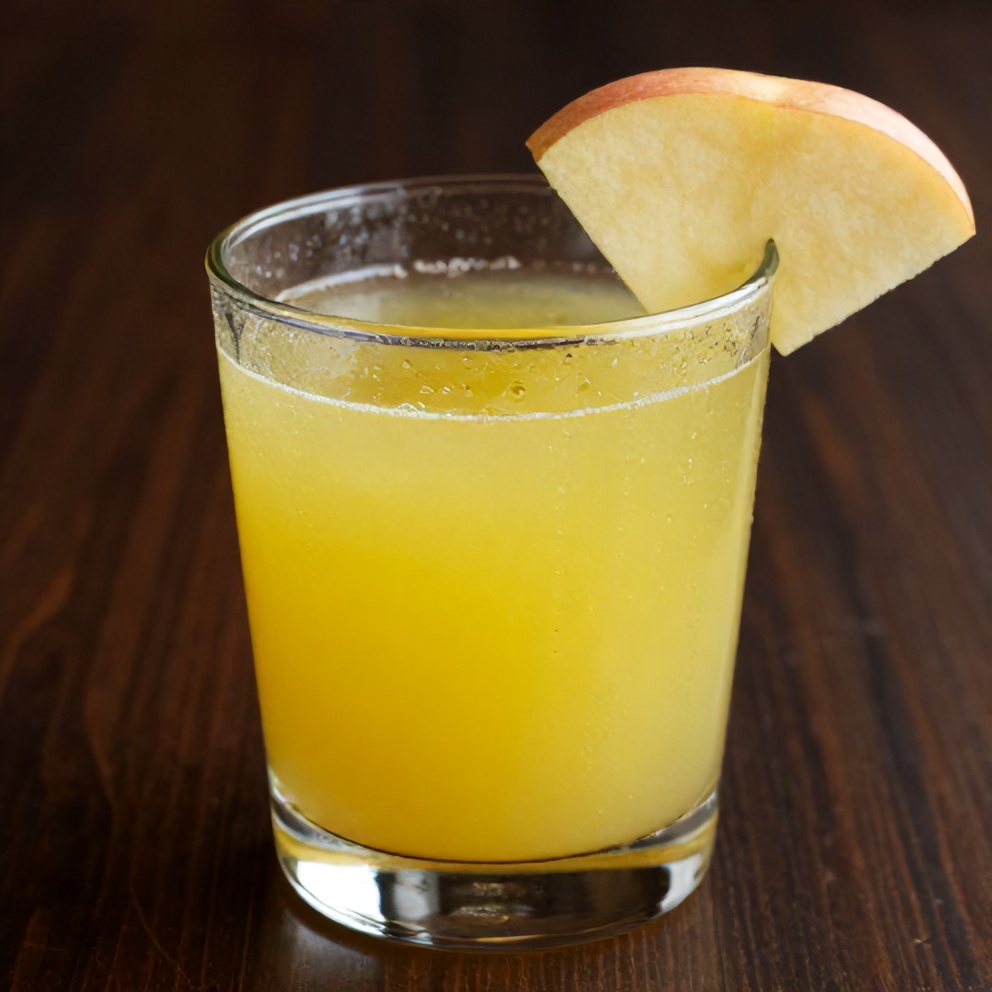 Glass of celery apple juice with a slice of apple on the rim